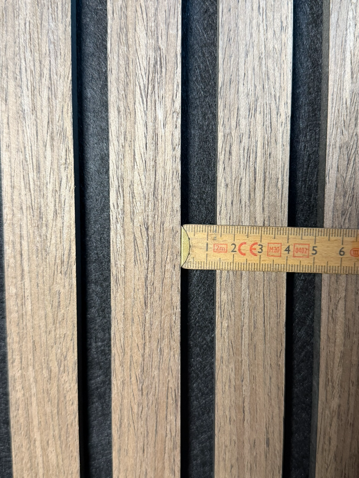 Akustikpanel med 13 mm mellemrum mellem lamellerne målt med tommestok